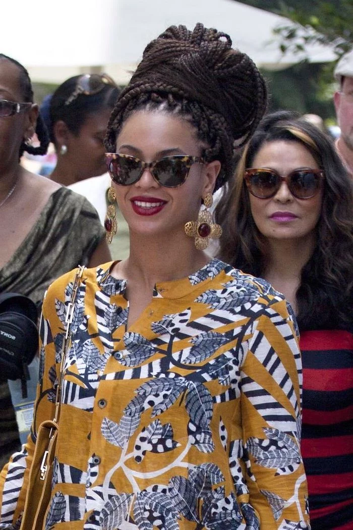 beyonce wearing an african print dress, hair in a large bun, straight back braids, large flower earrings
