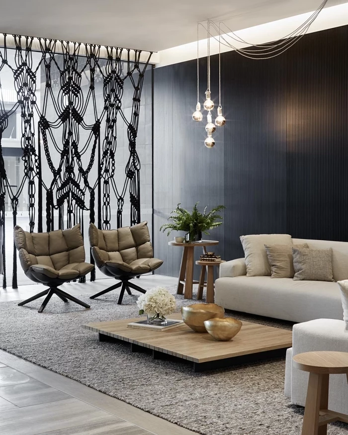 black accent wall, macrame wall hanging patterns, leather armchair, white corner sofa, wooden table