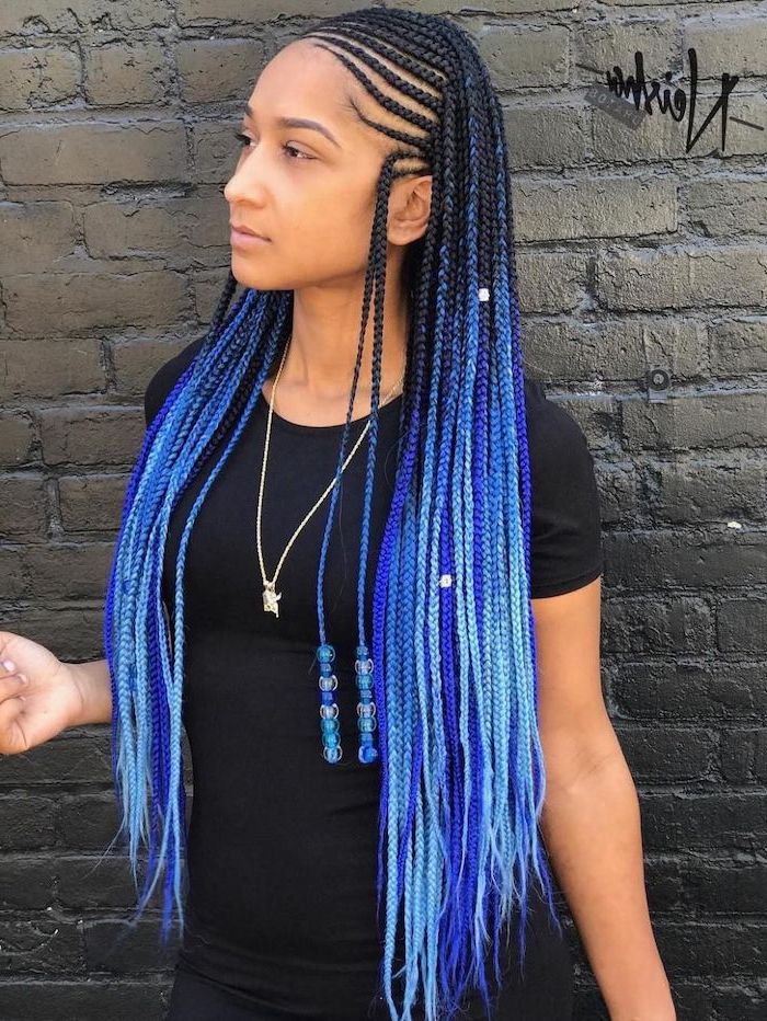black and blue hair with beads, cornrows to the side, woman standing in front of a black brick wall