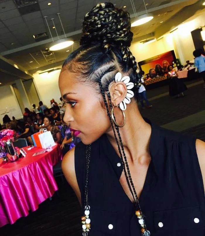 woman with black hair, in a bun with beads, female cornrow styles, wearing a black top