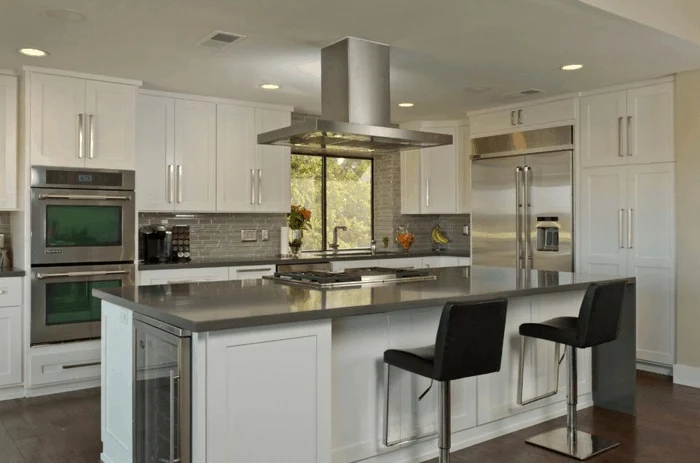 black leather chairs, white cabinets, kitchen island with sink, wooden floor, grey tiles backsplash