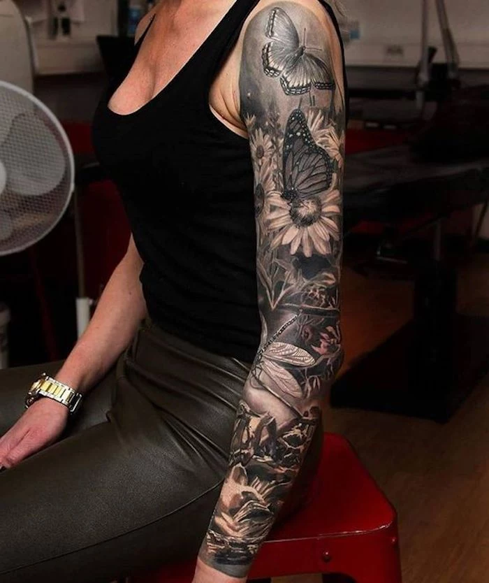 arm sleeve tattoo, chest tattoos for women, butterflies and flowers, black top, black leather pants