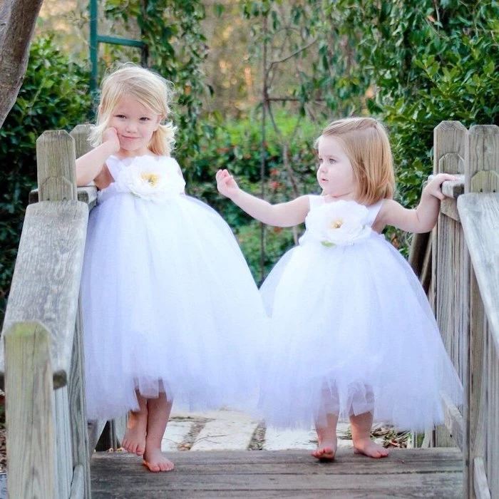 two girls, standing on a wooden bridge, dresses in white tulle dresses, flower girl dresses, short blonde hair