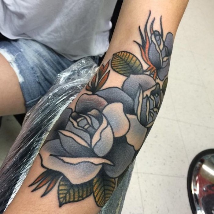 blue roses, arm tattoos for women, grey shirt, short jeans, white tiled floor