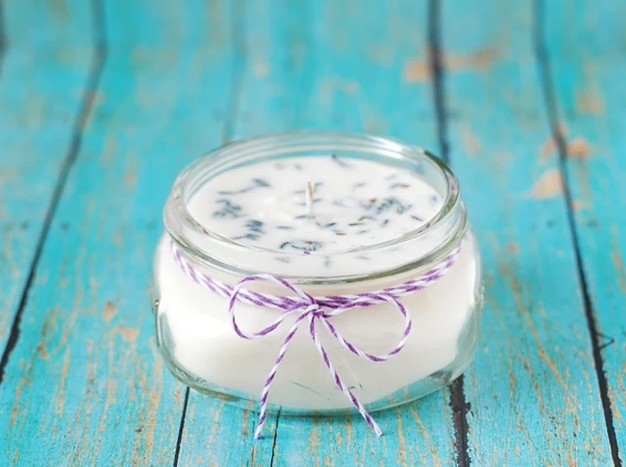 how to make a candle wick, small glass jar, candle wax inside, on a blue wooden table