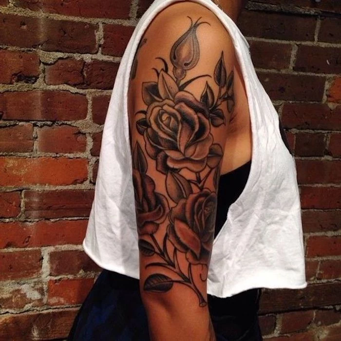 girl wearing a white top, roses and thorns, arm sleeve tattoo, in front of a brick wall, arm tattoos for girls