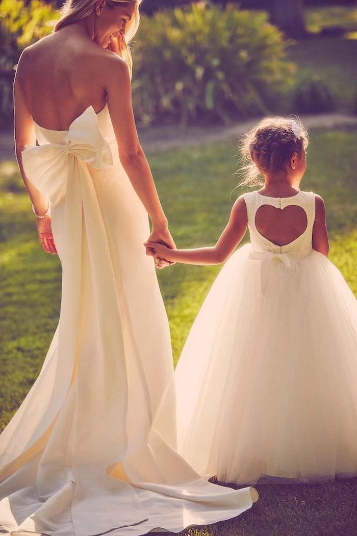 bride holding hands with flower girl, flower girl dresses, white dresses, heart shaped back, tulle bottom
