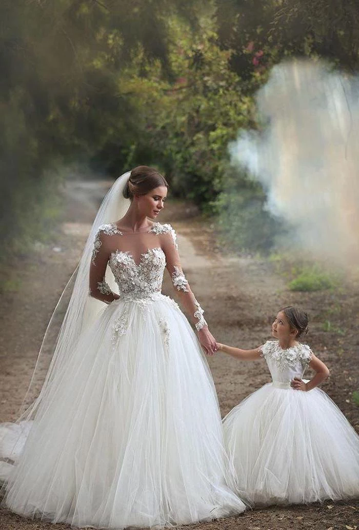 bride holding hands with a flower girl, dresses for girls, white lace and tulle dresses, on a pathway