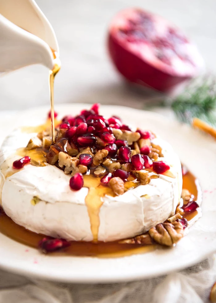 brie cheese, with honey and pomegranate, chopped nuts, dairy free appetizers, white plate