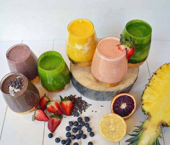 smoothies made with different ingredients, how to make a smoothie, sliced fruits, on a wooden table