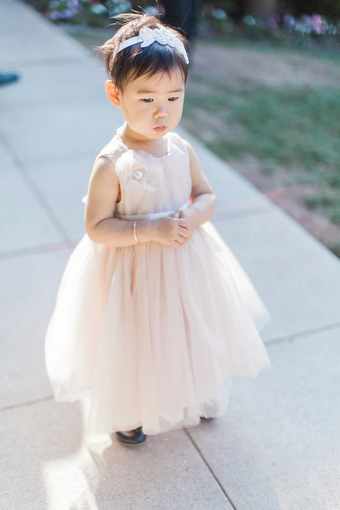 toddler girl, with a pixie cut, light pink tulle dress, girls party dresses, tiled floor, light pink diadem