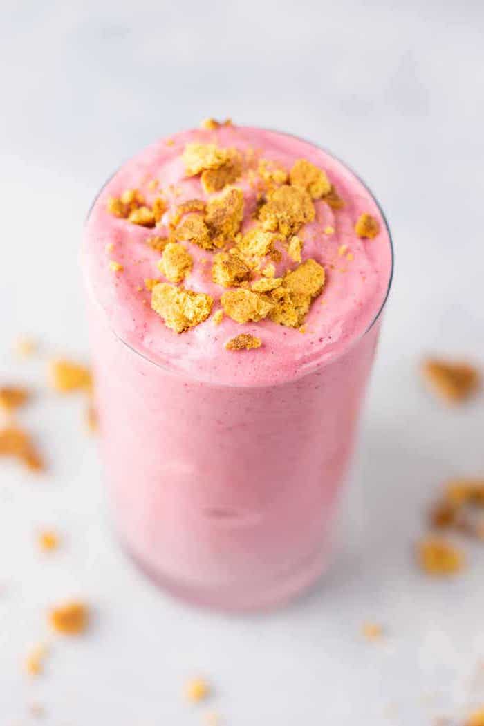 pink smoothie, in a tall glass, how to make a strawberry banana smoothie, cereal on top