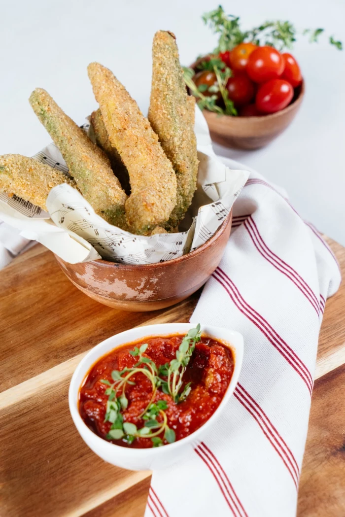 wooden cutting board, tomato sauce and cherry tomatoes in small bowls, finger food recipes, avocado fries