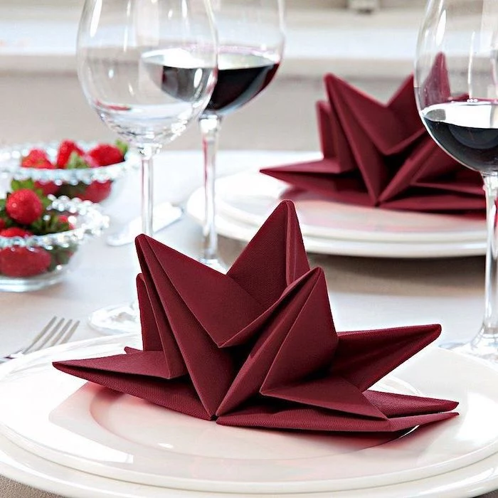star shaped, red napkin, napkin folding, wine glasses around, white plates