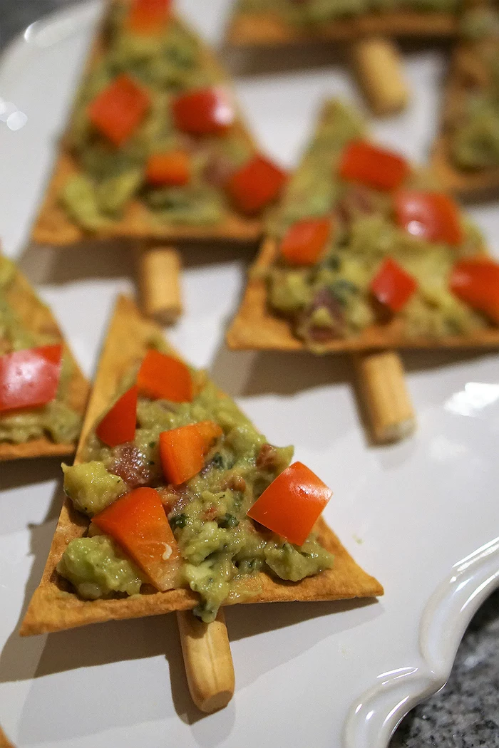 triangle shaped crackers, avocado and tomatoes on top, easy vegan appetizers, in a white plate
