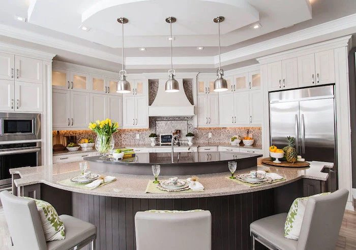 curved kitchen island, grey leather bar stools, green throw pillows, white cabinets, island countertop
