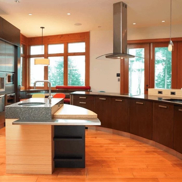 island countertop, wooden floor, curved kitchen island, wooden cabinets, black countertops