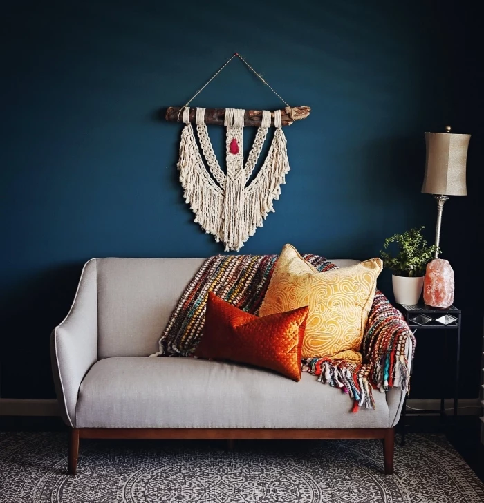 blue wall, macrame tutorial, grey sofa, red adn yellow throw pillows, colourful blanket