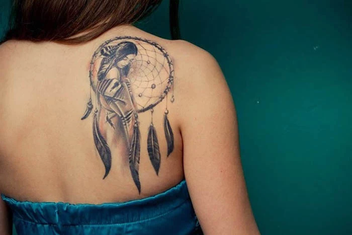 indian woman, large dreamcatcher, shoulder tattoo, upper arm tattoos, blue top, green background