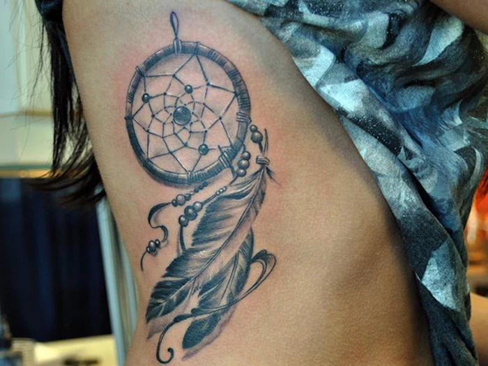 dreamcatcher with feathers, rib cage tattoo, upper arm tattoos, blue printed top