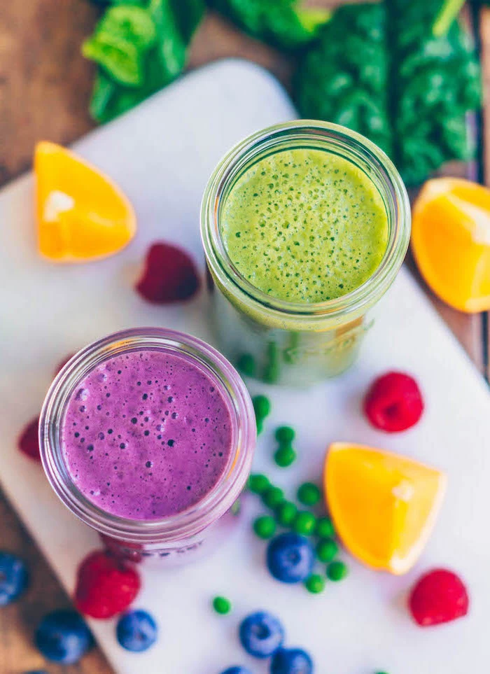 green and purple smoothie, green smoothie recipe, fruits scattered around, on a white board