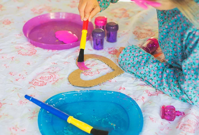 fun indoor activities for kids, blue and pink plastic plates, paint inside, girl painting a heart