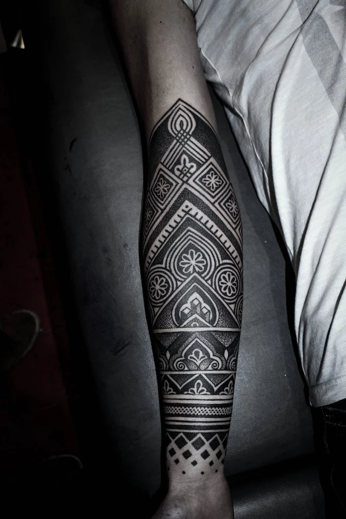 arm tattoos for girls, white top, black leather bed, geometrical forearm sleeve