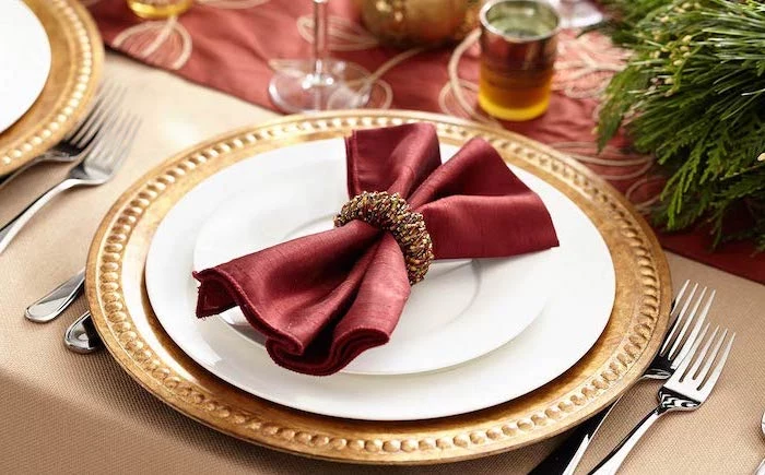 how to fold napkins, red bow shaped napkin, gold ring around it, on white and gold plates