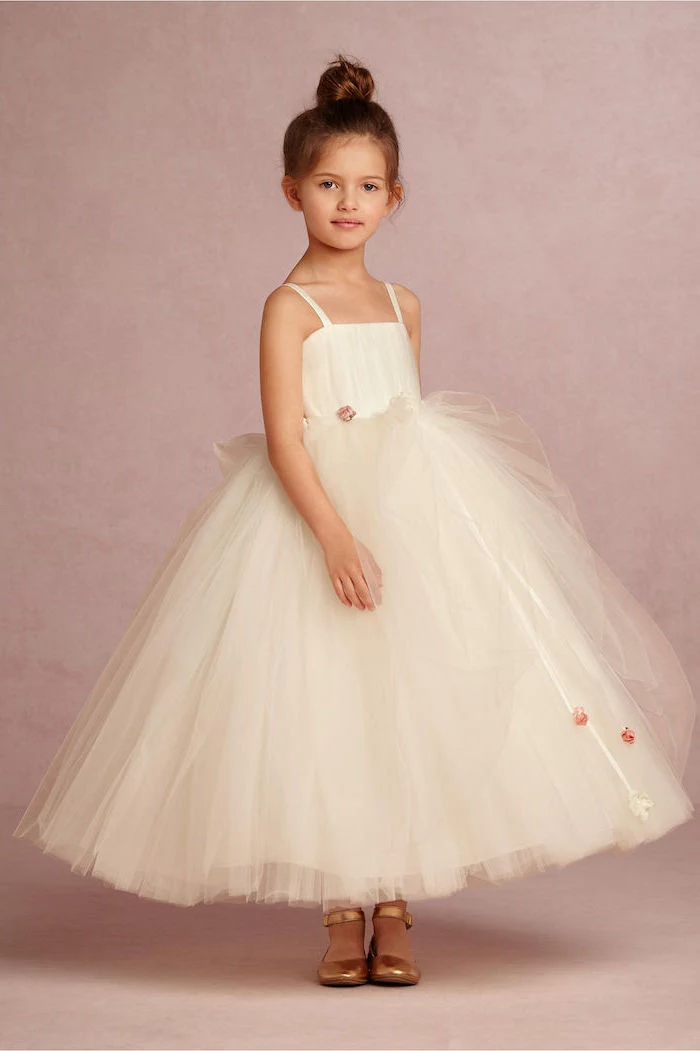 flower girl hair, white tulle dress, brown hair, messy bun, gold shoes, pink background