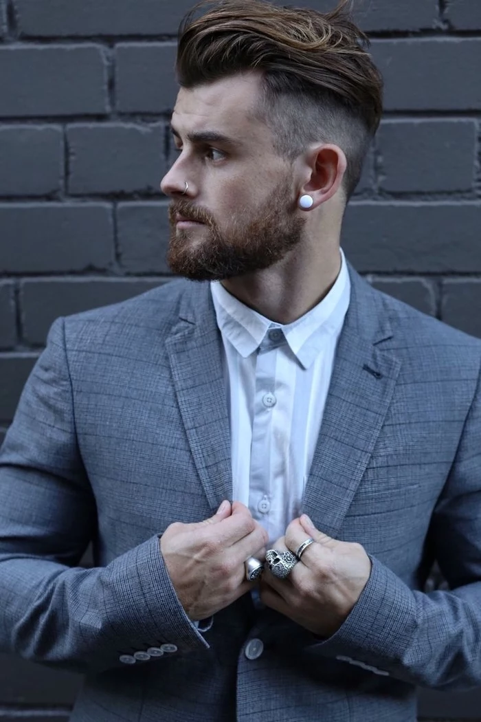 grey brick wall, grey jacket, white shirt, brown hair, cool haircuts for men, silver rings