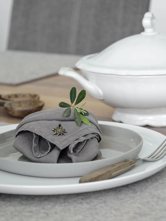 cloth napkin folding, grey napkin, in a grey plate, wooden fork handle