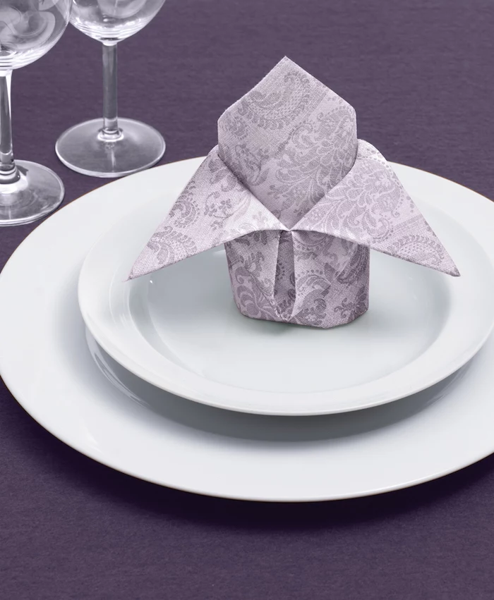 grey patterned napkin, on white plates, purple table cloth, cloth napkin folding