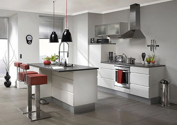 red leather bar stools, narrow kitchen island, white cabinets and drawers, black countertops, tiled floor