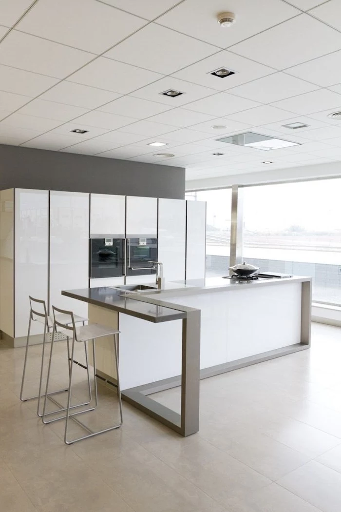 white tiled floor, metal bar stools, white cabinets, island cabinets, grey countertops, large windows