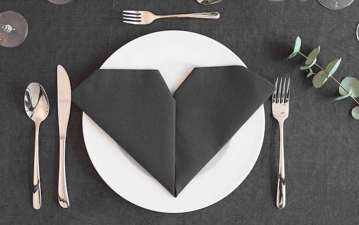 heart shaped, black napkin, on a white plate, fancy napkin folding, black table cloth