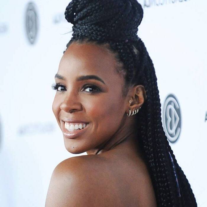 braiding styles with weave, kelly rowland smiling, with black hair, in a bun, small earrings