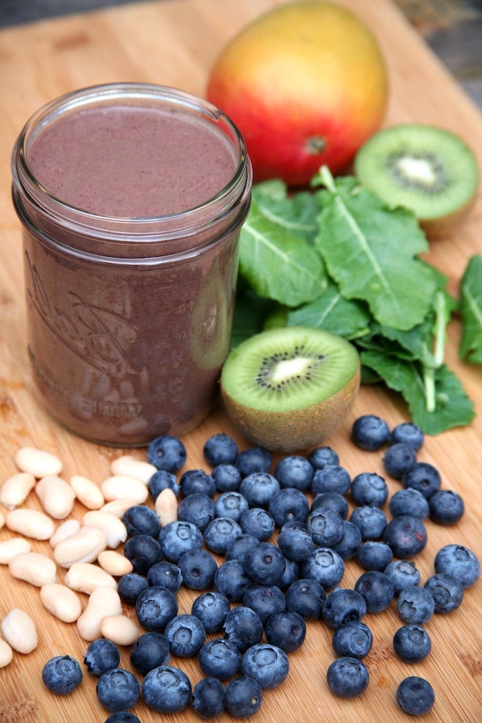 protein smoothie recipes, kiwi slices, berries and peanuts, apple and spinach, on a wooden board