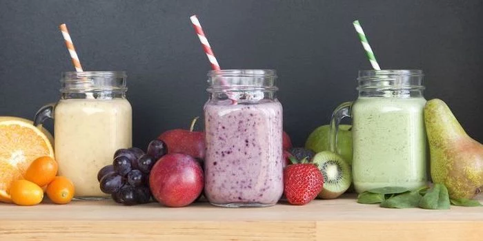 healthy smoothie recipes, jars filled with different smoothies, orange and cherry tomatoes, different fruits