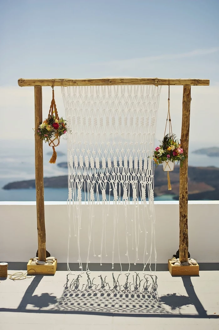 large wooden arch, plant hangers, flower bouquets, macrame hanging, blue sky and ocean
