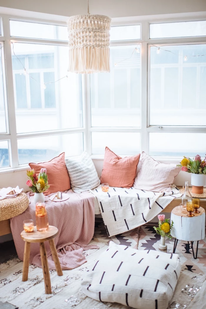 pink and white throw pillows, how to macrame, pink blanket, small wooden tables, large windows