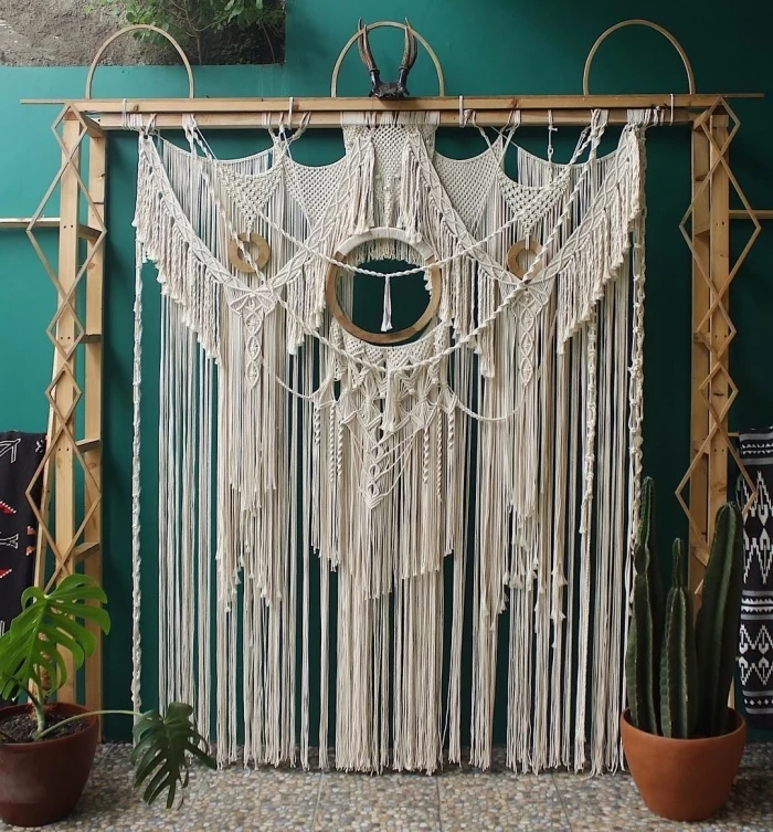 large wooden arch, macrame hanging, white macrame curtain, potted plant and cactus