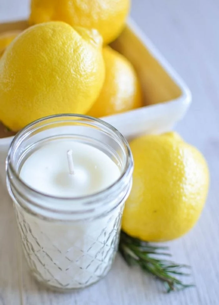 lemons in a white bowl, essential oil candles, white candle wax, in a glass jar, on a wooden table