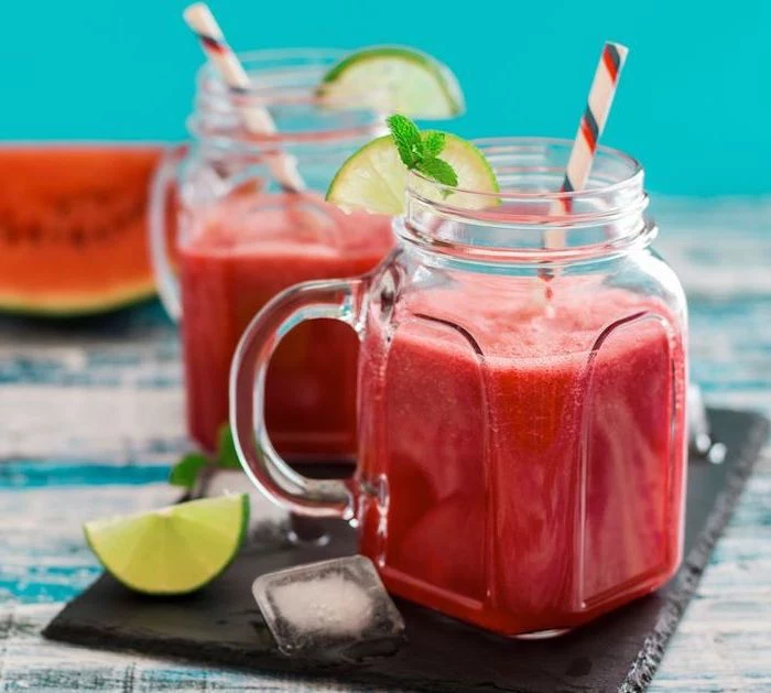 how to make a smoothie with frozen fruit, two jars, lime slices on the rim, ice cubes