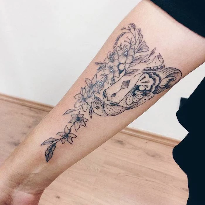 feminine tattoos, lion head and flowers, forearm tattoo, wooden floor