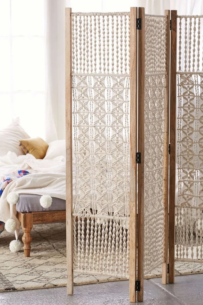 wooden room divider with macrame, macrame hanging, cement floor, white wall, wooden bed frame