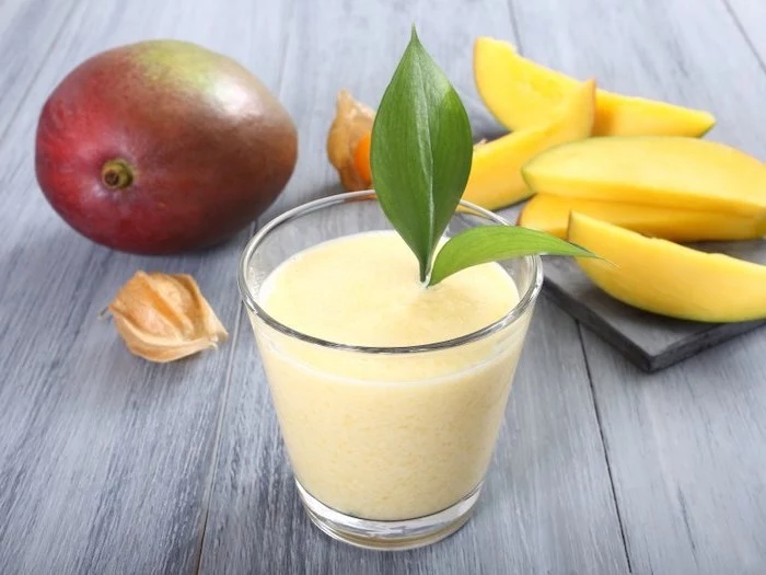 how to make a smoothie with frozen fruit, mango slices, on a ceramic board, wooden table