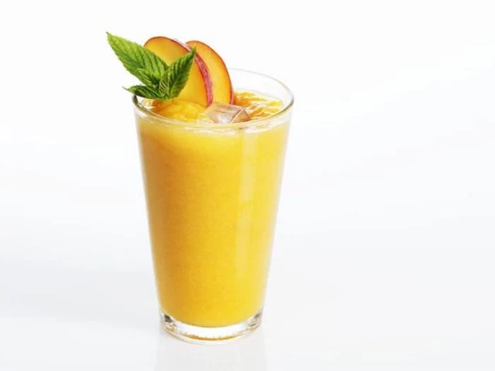 tall glass, how to make a smoothie with frozen fruit, mango slices on the rim, mint on top