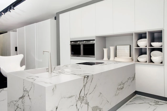 marble kitchen island and floor, white cabinets, open shelving, white armchair, kitchen island countertop