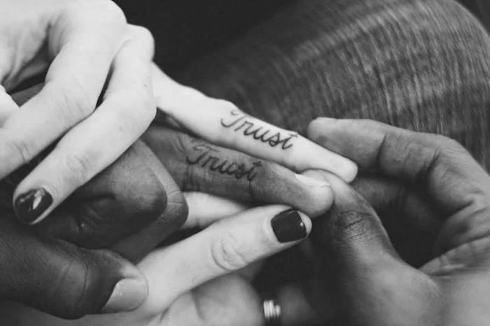 trust inside finger tattoos, black nail polish, black and white photo, unique couple tattoos