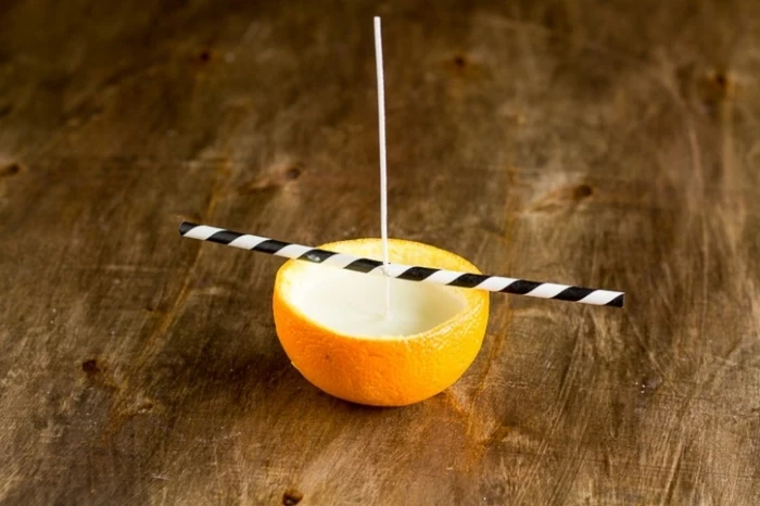 orange peel, filled with candle wax, how to make candles at home, wooden table